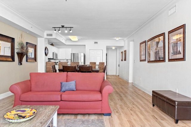 living room with track lighting, light hardwood / wood-style flooring, and ornamental molding