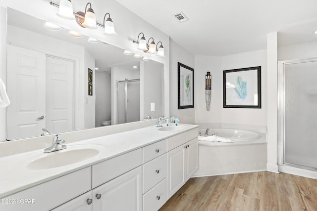 full bathroom featuring hardwood / wood-style flooring, vanity, separate shower and tub, and toilet