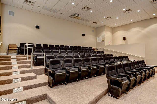 carpeted home theater featuring a drop ceiling and a high ceiling