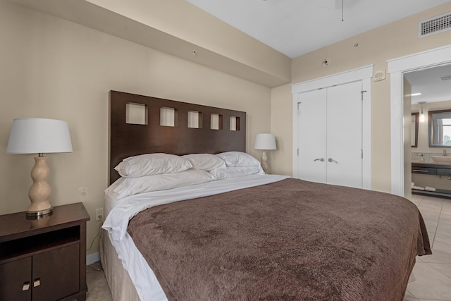 bedroom with ensuite bath, a closet, and light tile flooring