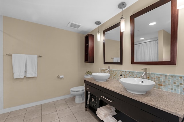 bathroom featuring tasteful backsplash, toilet, vanity with extensive cabinet space, and dual sinks