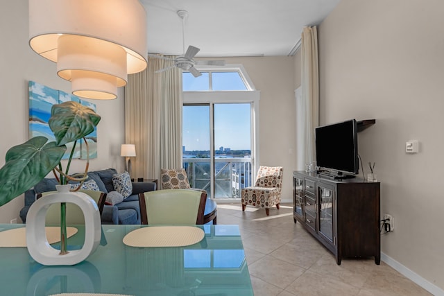 living room with a water view, ceiling fan, and light tile flooring