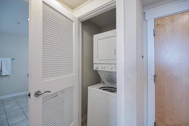 clothes washing area with stacked washer and dryer and light tile floors