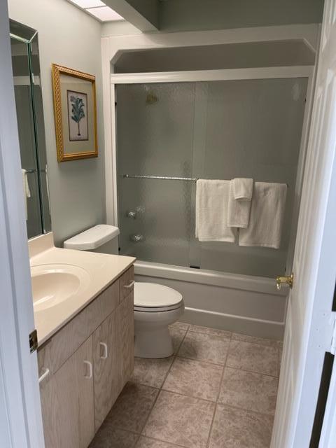 full bathroom featuring enclosed tub / shower combo, toilet, tile floors, and vanity