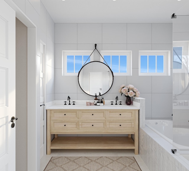 bathroom featuring tiled tub, tile walls, and double sink vanity