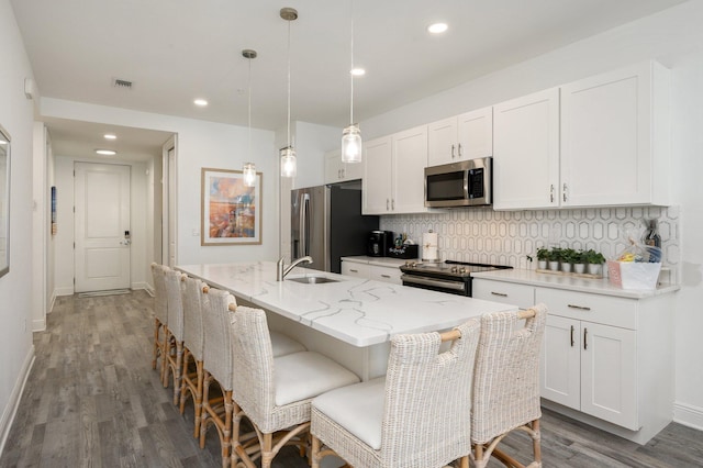 kitchen with a center island with sink, appliances with stainless steel finishes, backsplash, and white cabinetry