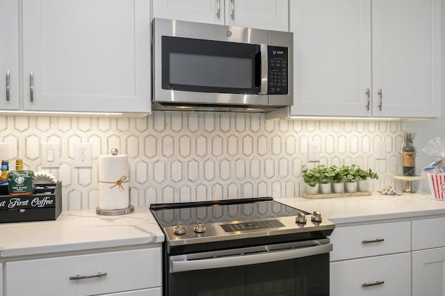 kitchen featuring light stone counters, appliances with stainless steel finishes, tasteful backsplash, and white cabinetry