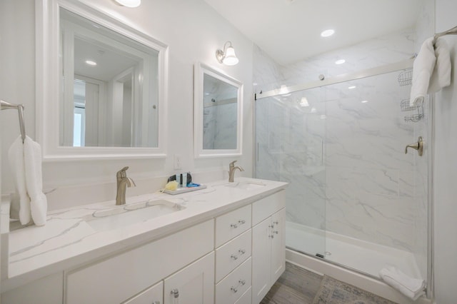 bathroom featuring oversized vanity, an enclosed shower, hardwood / wood-style flooring, and dual sinks