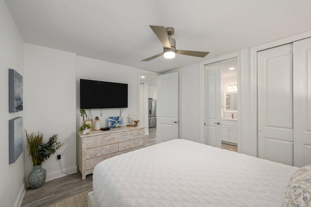 bedroom with ensuite bathroom, ceiling fan, wood-type flooring, stainless steel refrigerator with ice dispenser, and a closet