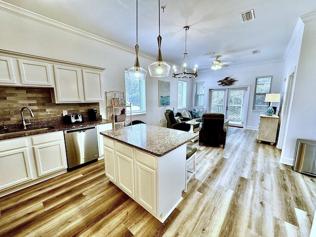 kitchen featuring plenty of natural light, backsplash, sink, stainless steel dishwasher, and light hardwood / wood-style floors