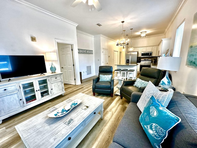 living room featuring ceiling fan with notable chandelier, crown molding, and light hardwood / wood-style floors