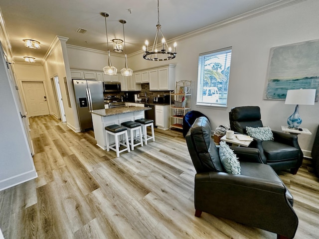 living room featuring light hardwood / wood-style flooring, a chandelier, and ornamental molding