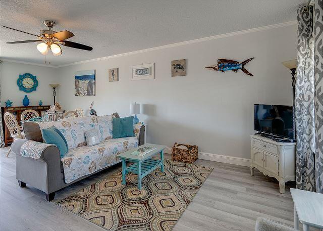 living room with ornamental molding, ceiling fan, light wood-type flooring, and a textured ceiling