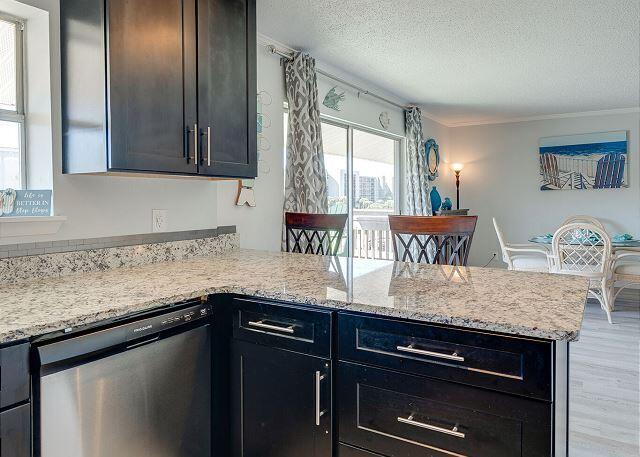 kitchen with light stone counters, dishwasher, a textured ceiling, and light wood-type flooring