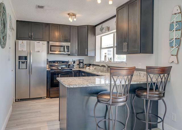 kitchen featuring stainless steel appliances, light hardwood / wood-style flooring, kitchen peninsula, a kitchen breakfast bar, and light stone countertops