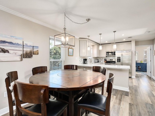 dining area with light hardwood / wood-style floors, a chandelier, and ornamental molding