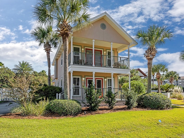 view of front of property with covered porch, a balcony, and a front lawn