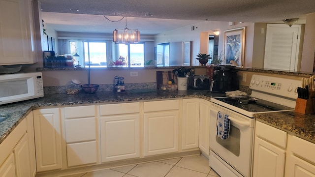 kitchen with light tile patterned floors, a textured ceiling, a chandelier, dark stone counters, and white appliances