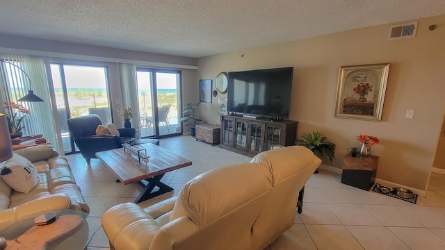 living area with tile patterned flooring, visible vents, a textured ceiling, and baseboards