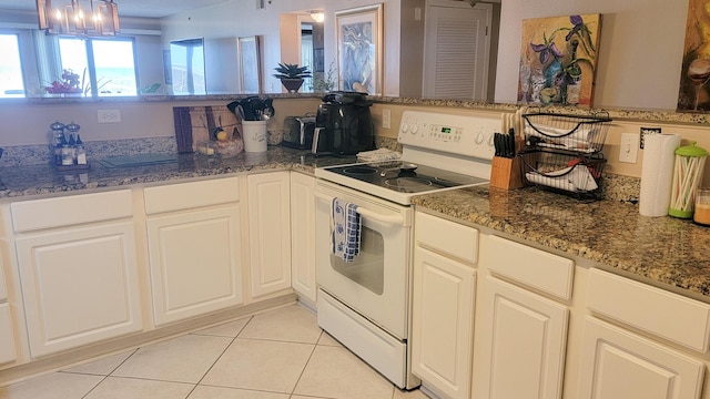 kitchen with light tile patterned flooring, white electric stove, and dark stone countertops