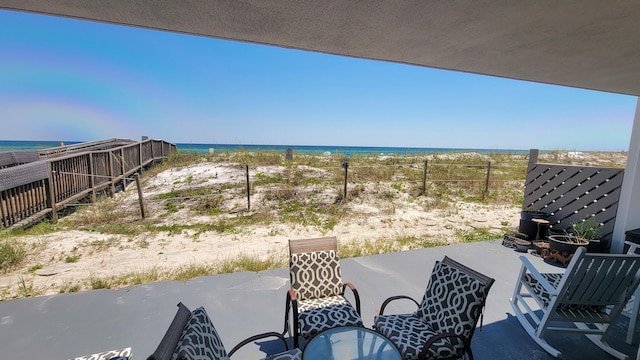 view of patio featuring a water view, fence, and a view of the beach