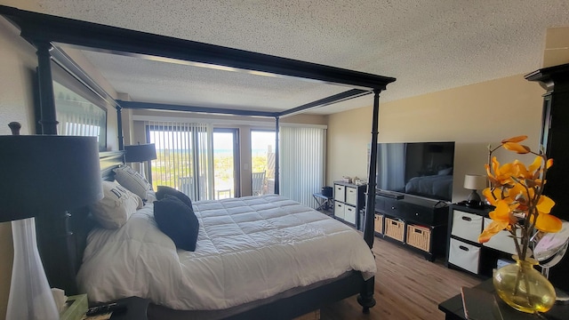 bedroom with access to exterior, a textured ceiling, and wood finished floors