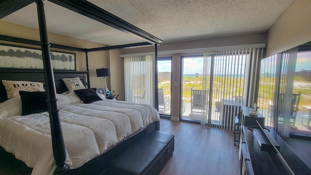 bedroom featuring access to exterior, a textured ceiling, and wood finished floors