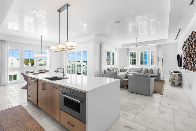 kitchen featuring decorative light fixtures, light tile flooring, stainless steel appliances, a center island with sink, and sink