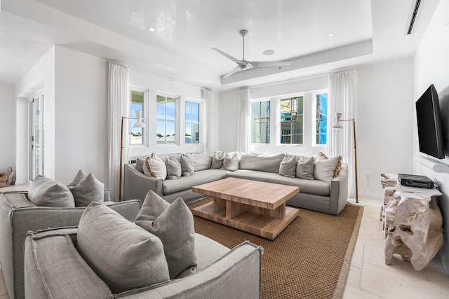 tiled living room with a healthy amount of sunlight, a raised ceiling, and ceiling fan