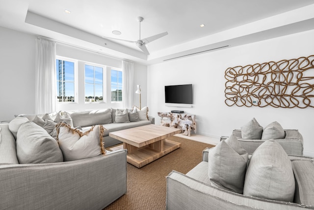 living room featuring a raised ceiling and ceiling fan