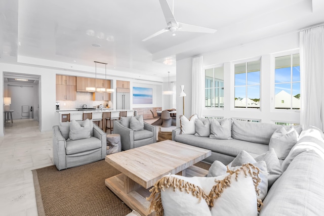 living room featuring ceiling fan and a raised ceiling