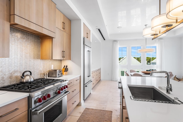 kitchen featuring hanging light fixtures, premium appliances, backsplash, sink, and light tile floors