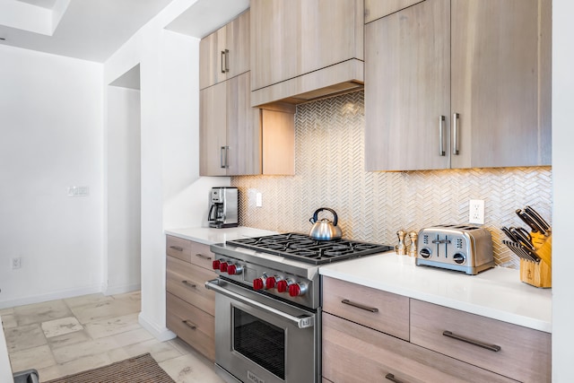 kitchen featuring light brown cabinets, luxury stove, tasteful backsplash, and light tile floors