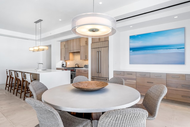 dining area with sink, a raised ceiling, light tile floors, and a notable chandelier