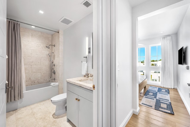 full bathroom with hardwood / wood-style floors, vanity, shower / bath combo, and toilet