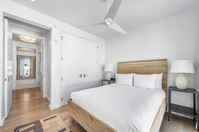 bedroom with a closet, light hardwood / wood-style floors, and ceiling fan