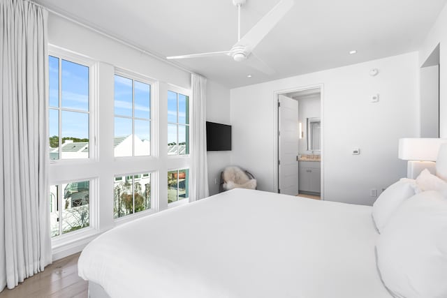 bedroom with ensuite bath, light hardwood / wood-style flooring, and multiple windows