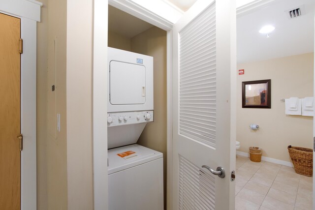 laundry room with light tile flooring and stacked washing maching and dryer