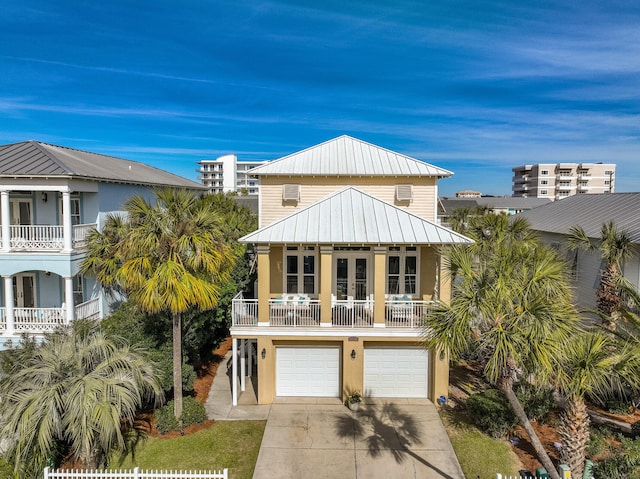 raised beach house featuring a garage, a balcony, and french doors