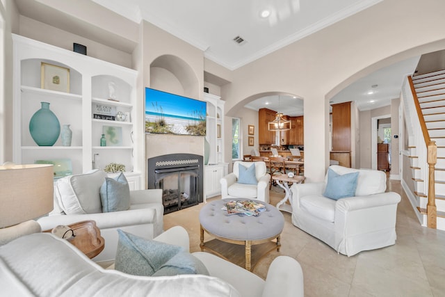 tiled living room featuring built in shelves, crown molding, and a chandelier