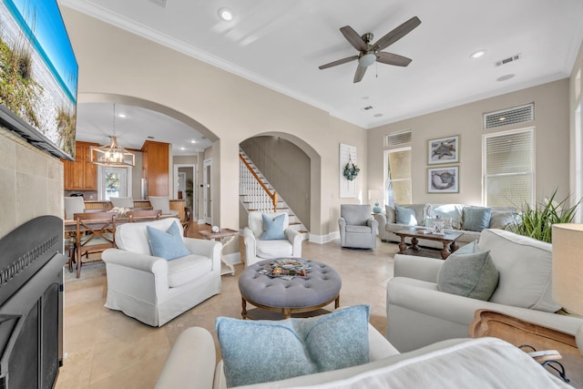 living room featuring ceiling fan with notable chandelier and crown molding