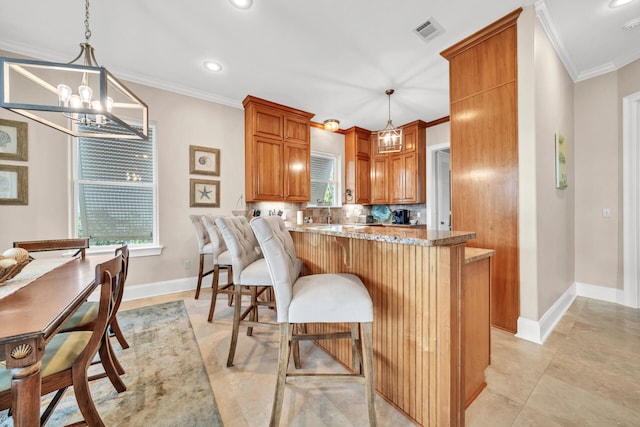 kitchen featuring kitchen peninsula, hanging light fixtures, and ornamental molding