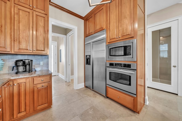 kitchen with light stone counters, built in appliances, crown molding, decorative backsplash, and light tile patterned floors