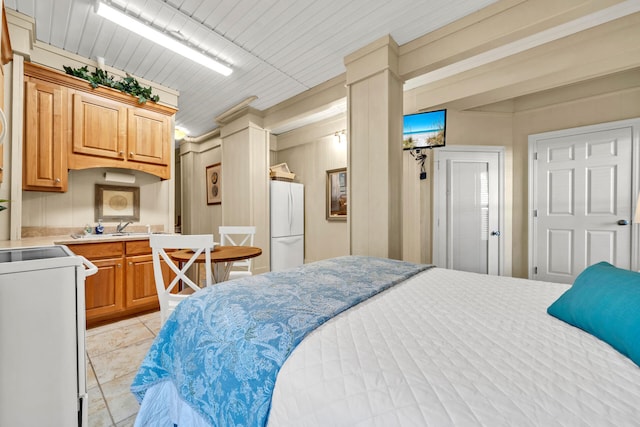 bedroom featuring crown molding, sink, light tile patterned floors, and white refrigerator