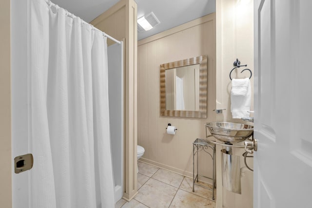 bathroom with toilet, tile patterned flooring, and sink