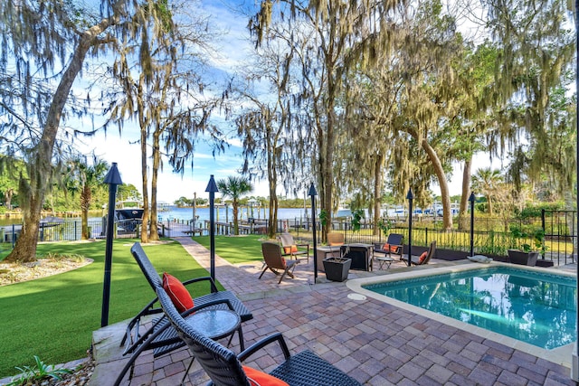 view of swimming pool featuring a water view, a patio, an outdoor fire pit, and a lawn