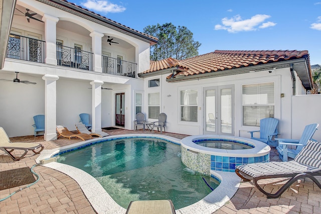 rear view of house with a patio area, ceiling fan, a pool with hot tub, french doors, and a balcony