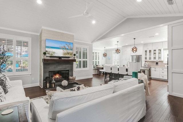 living room featuring ceiling fan, dark hardwood / wood-style flooring, a large fireplace, and ornamental molding