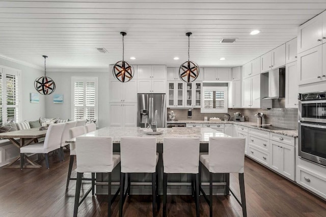 kitchen with plenty of natural light, appliances with stainless steel finishes, dark wood-type flooring, and a breakfast bar