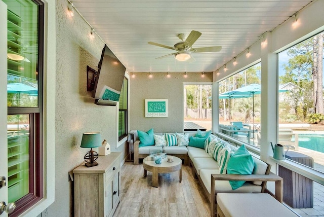 sunroom featuring ceiling fan and track lighting